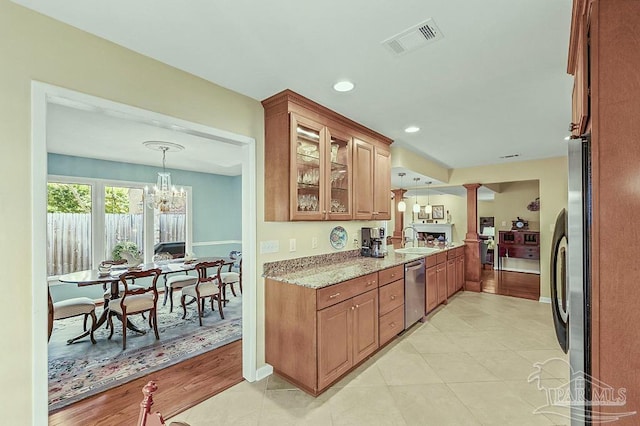 kitchen featuring a sink, visible vents, stainless steel dishwasher, brown cabinets, and glass insert cabinets