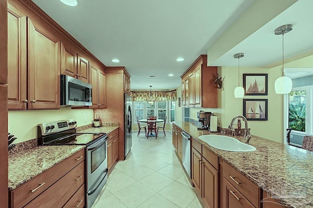 kitchen with stainless steel appliances, a sink, hanging light fixtures, and light stone countertops