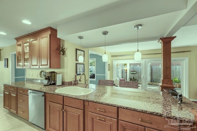 kitchen with light stone countertops, dishwasher, decorative columns, and a sink