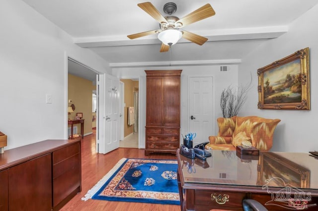 office space with a ceiling fan, visible vents, and wood finished floors