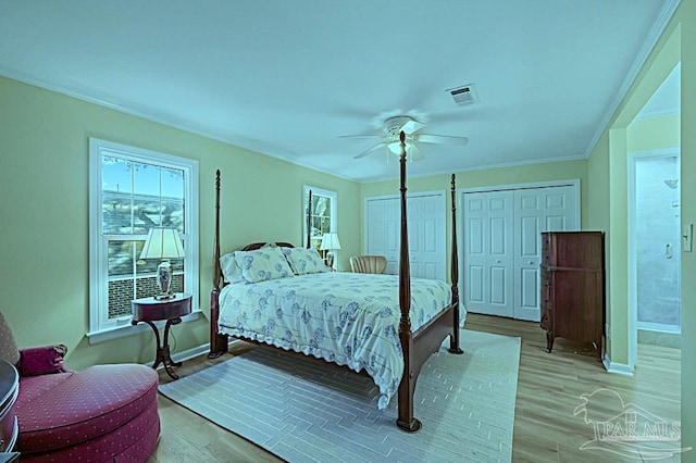 bedroom with light wood finished floors, visible vents, and crown molding