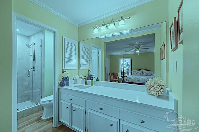 ensuite bathroom featuring toilet, wood finished floors, crown molding, vanity, and a shower stall