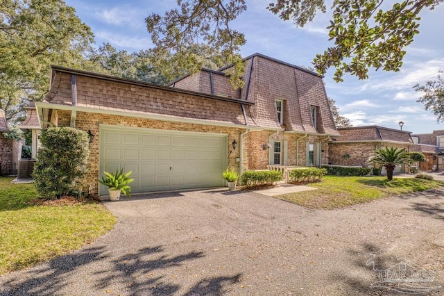 view of front of property with driveway, mansard roof, an attached garage, and brick siding