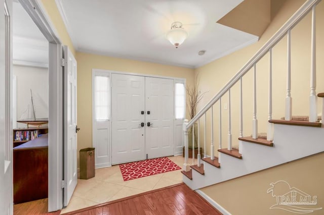 entryway with stairs, wood finished floors, and crown molding