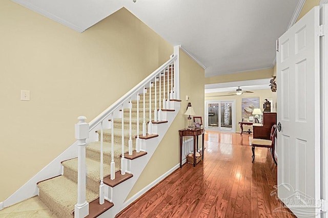 stairs featuring ornamental molding, ceiling fan, baseboards, and wood finished floors