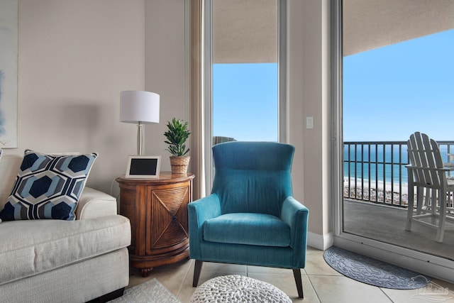 living area featuring a wealth of natural light, a water view, and light tile patterned floors