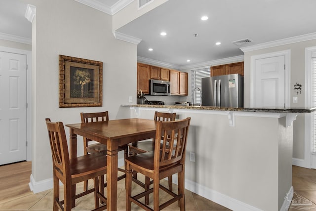 dining space featuring crown molding, sink, and light tile patterned flooring