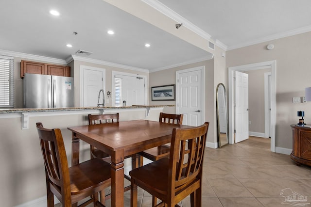 dining area with ornamental molding, sink, and light tile patterned flooring