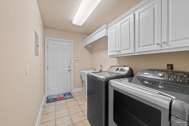 laundry room with light tile patterned floors, electric panel, cabinets, and washing machine and clothes dryer