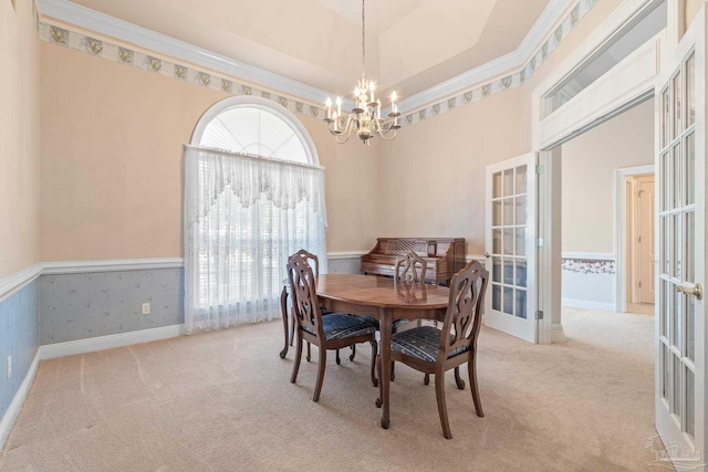 dining space with ornamental molding, light colored carpet, a notable chandelier, and french doors