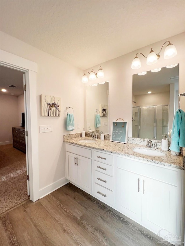 bathroom with hardwood / wood-style flooring, vanity, and an enclosed shower