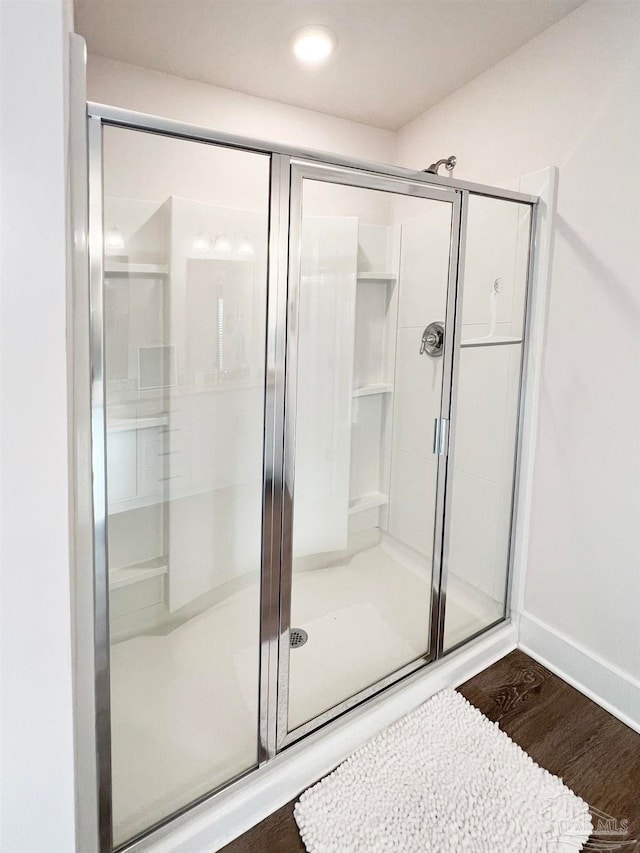 bathroom featuring a shower with shower door and hardwood / wood-style floors