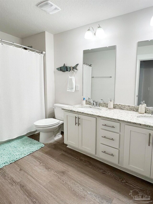 bathroom with vanity, toilet, curtained shower, a textured ceiling, and hardwood / wood-style floors