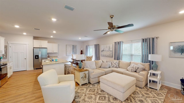 living room with light wood-type flooring and ceiling fan