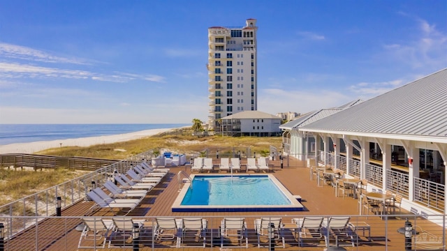 view of pool with a patio, a water view, and a beach view