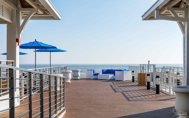 wooden terrace with a water view and outdoor lounge area