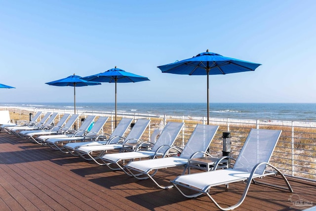 wooden deck with a water view and a beach view