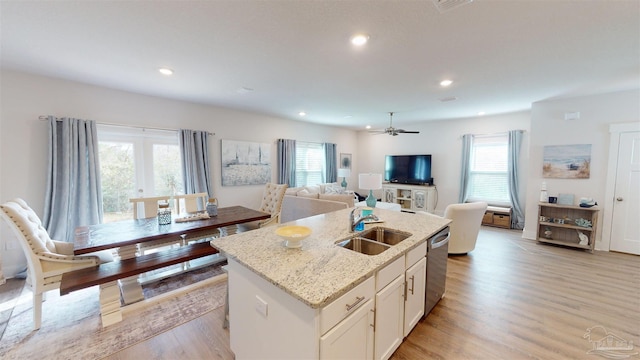 kitchen featuring light wood-type flooring, a healthy amount of sunlight, and an island with sink