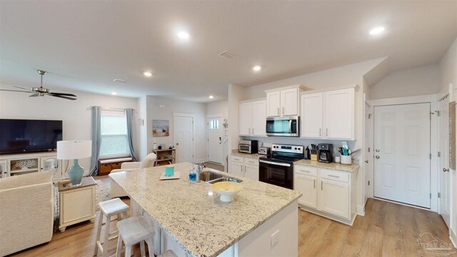 kitchen with an island with sink, appliances with stainless steel finishes, and white cabinetry