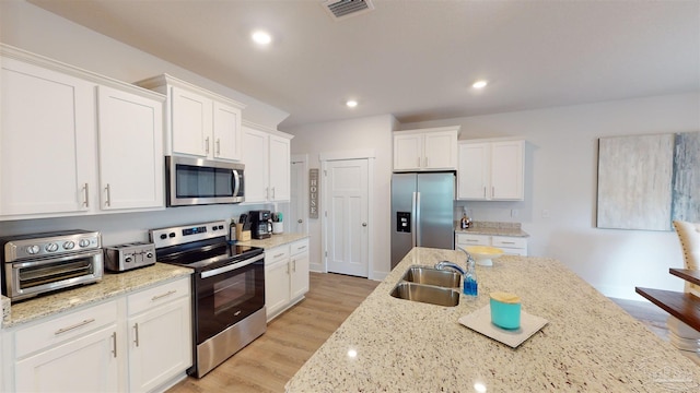 kitchen featuring appliances with stainless steel finishes, light hardwood / wood-style floors, sink, and white cabinets