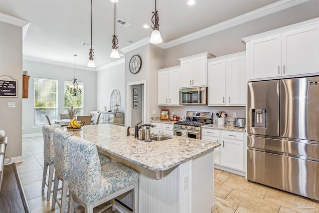 kitchen featuring white cabinets, stainless steel appliances, sink, hanging light fixtures, and a kitchen island with sink