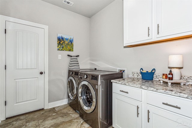 clothes washing area with cabinets and washer and dryer