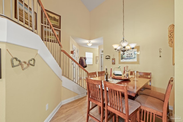 dining room featuring an inviting chandelier, light hardwood / wood-style floors, and a high ceiling