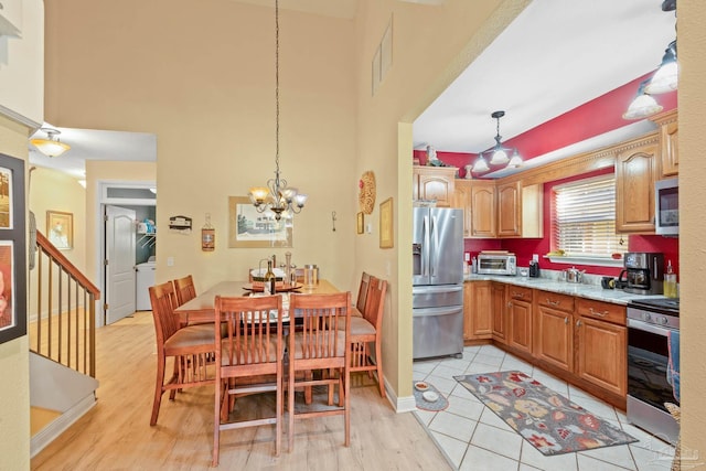 kitchen with pendant lighting, light hardwood / wood-style flooring, stainless steel appliances, and an inviting chandelier