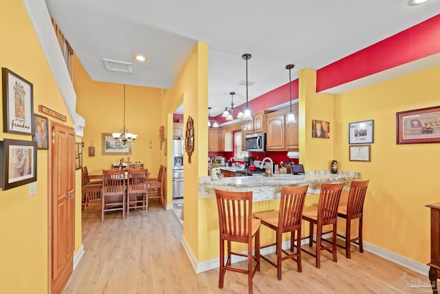 kitchen featuring stainless steel appliances, a breakfast bar, light hardwood / wood-style floors, and kitchen peninsula