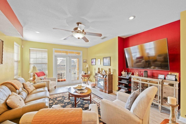 living room featuring a textured ceiling, french doors, ceiling fan, and light wood-type flooring