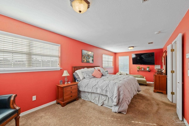 bedroom featuring light colored carpet and a textured ceiling