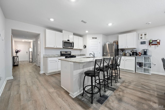 4616 Honor Guard Way, Crestview, FL 32539 - kitchen with stainless steel appliances, light wood-style floors, a kitchen breakfast bar, an island with sink, and white cabinets