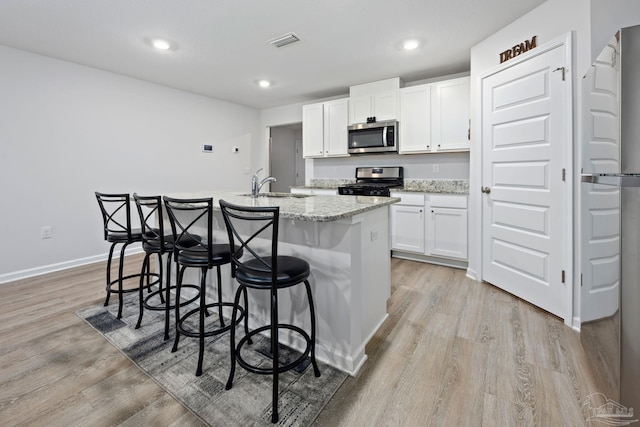 4616 Honor Guard Way, Crestview, FL 32539 - kitchen featuring stainless steel appliances, light wood-style floors, white cabinets, an island with sink, and a breakfast bar area