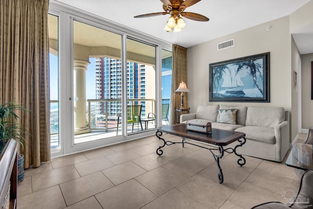 living room with ceiling fan, light tile patterned flooring, and a textured ceiling