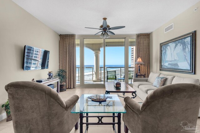 living room featuring light tile patterned floors, a textured ceiling, and ceiling fan