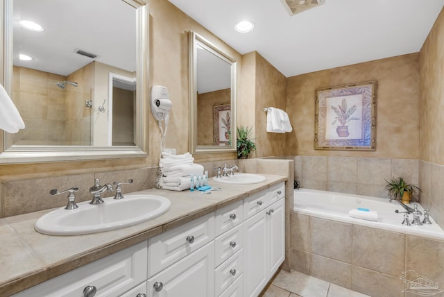 bathroom with tiled tub, tile patterned flooring, and vanity