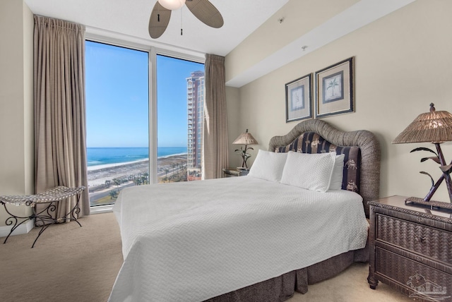 bedroom with carpet, ceiling fan, and a water view