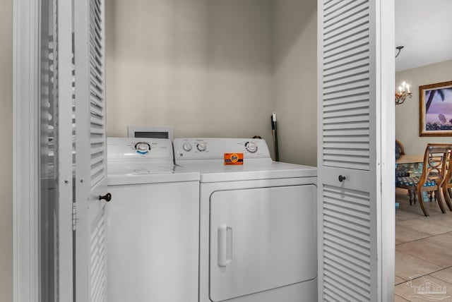 laundry room with washing machine and clothes dryer, light tile patterned floors, and a notable chandelier