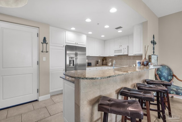 kitchen with white cabinets, stainless steel fridge, and kitchen peninsula