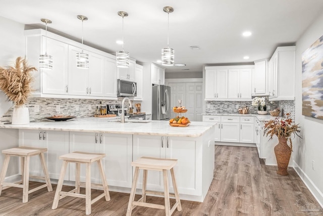 kitchen featuring white cabinets, decorative backsplash, stainless steel appliances, and kitchen peninsula