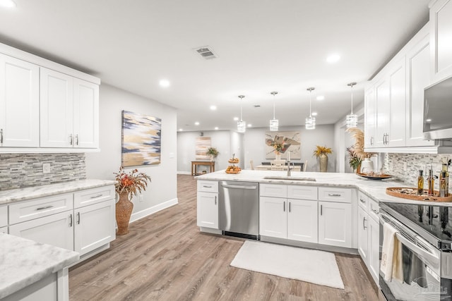 kitchen with pendant lighting, kitchen peninsula, sink, appliances with stainless steel finishes, and white cabinetry