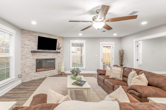 living room with plenty of natural light, ceiling fan, a fireplace, and light hardwood / wood-style flooring