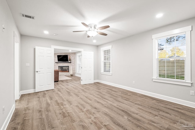 unfurnished living room with a fireplace, light wood-type flooring, and ceiling fan