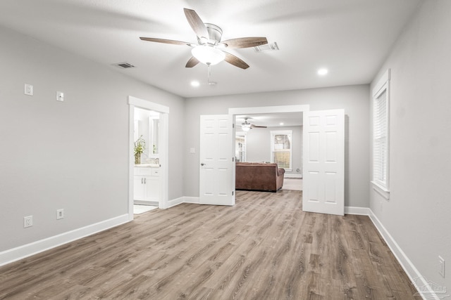 unfurnished bedroom with light wood-type flooring, ensuite bathroom, and ceiling fan