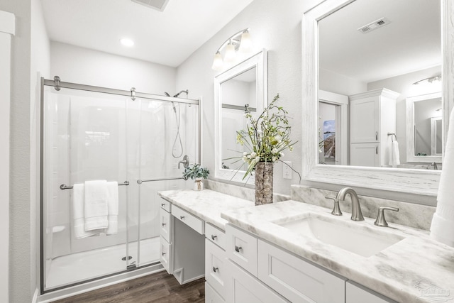 bathroom with vanity, hardwood / wood-style flooring, and a shower with door