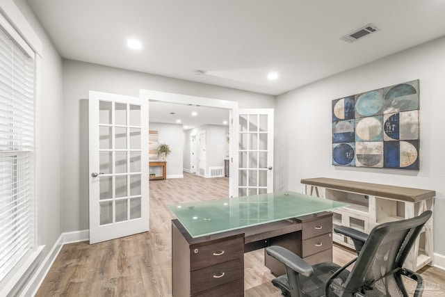 office featuring a healthy amount of sunlight, light wood-type flooring, and french doors