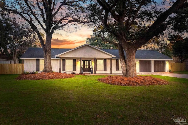 ranch-style house featuring a garage, a yard, and french doors