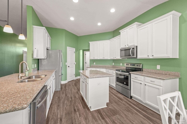 kitchen with a kitchen island, appliances with stainless steel finishes, a sink, dark wood-style floors, and white cabinetry