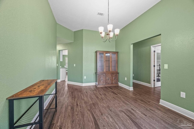 unfurnished dining area with an inviting chandelier, baseboards, wood finished floors, and visible vents
