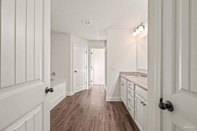 full bathroom with a textured ceiling, visible vents, wood finished floors, vanity, and baseboards